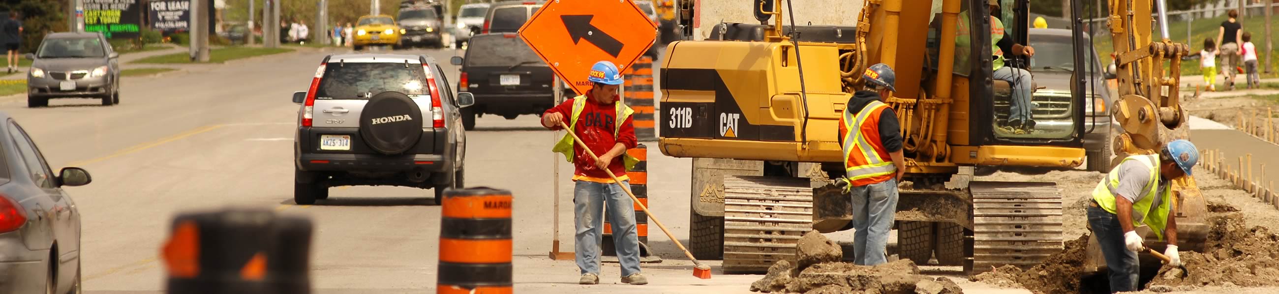 Construction workers digging a hole on a street in Barrie.